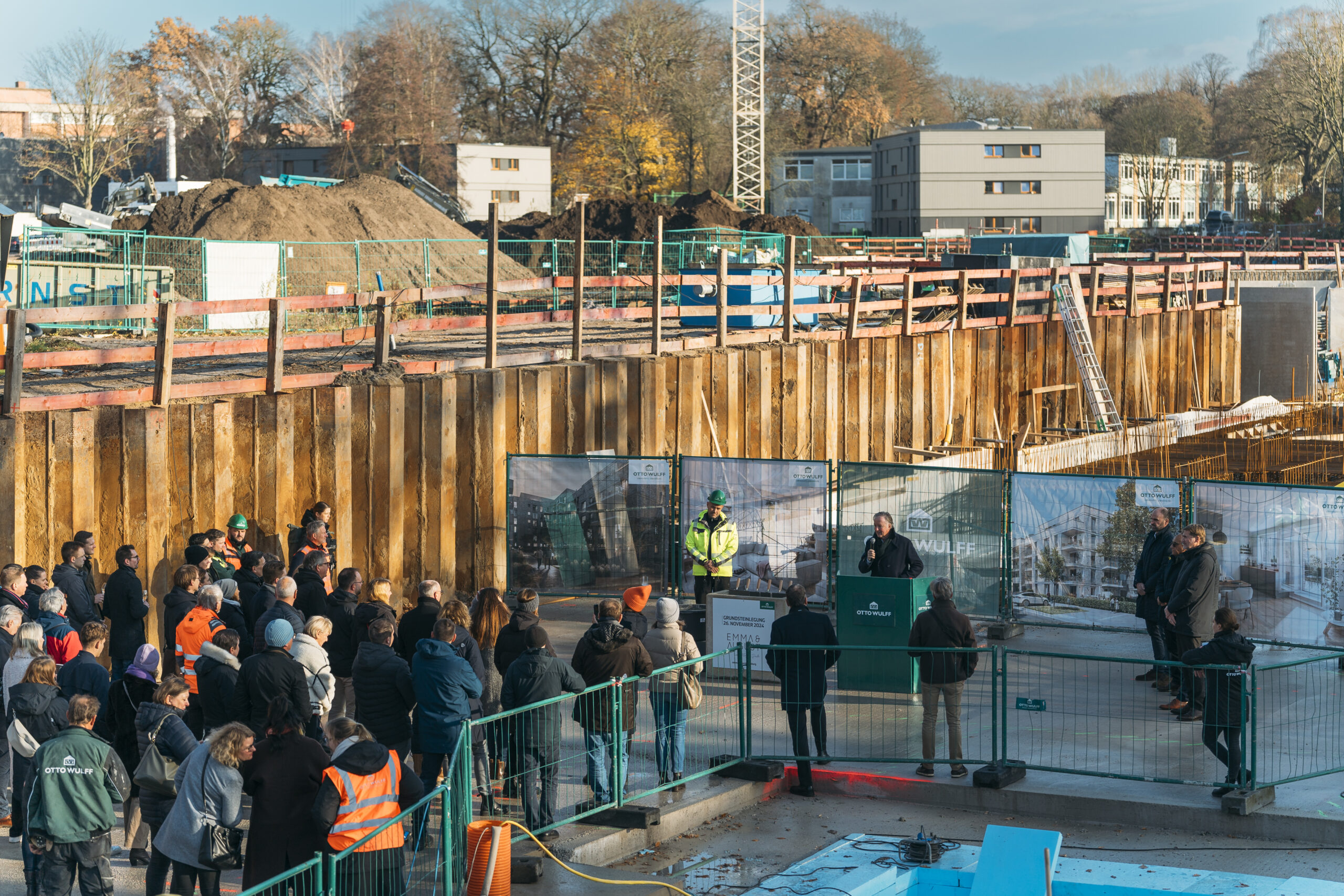 Menschen versammeln sich bei einer Rede auf einer Baustelle im Freien.