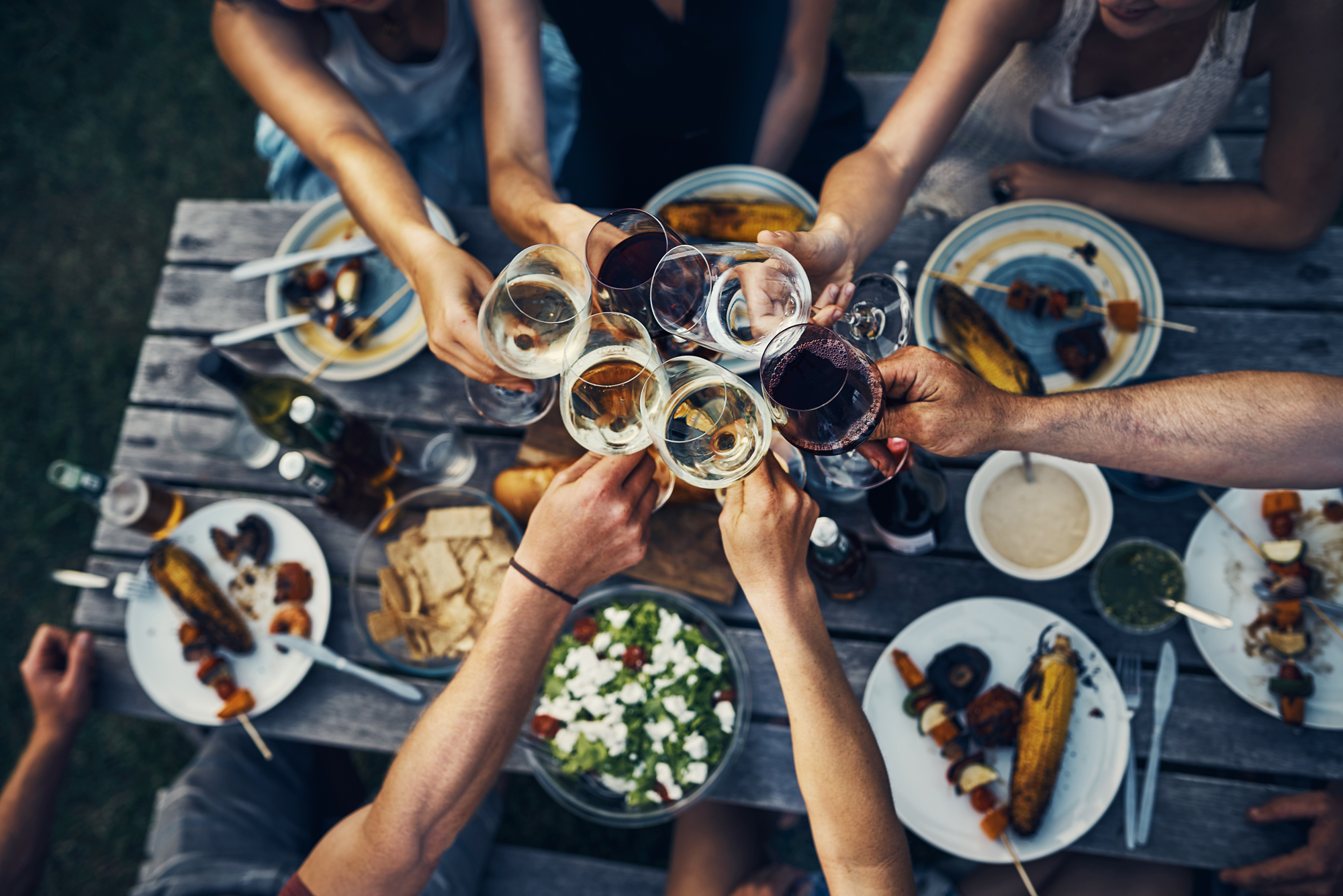 grillparty Menschen stoßen beim Essen im Freien mit Weingläsern an.