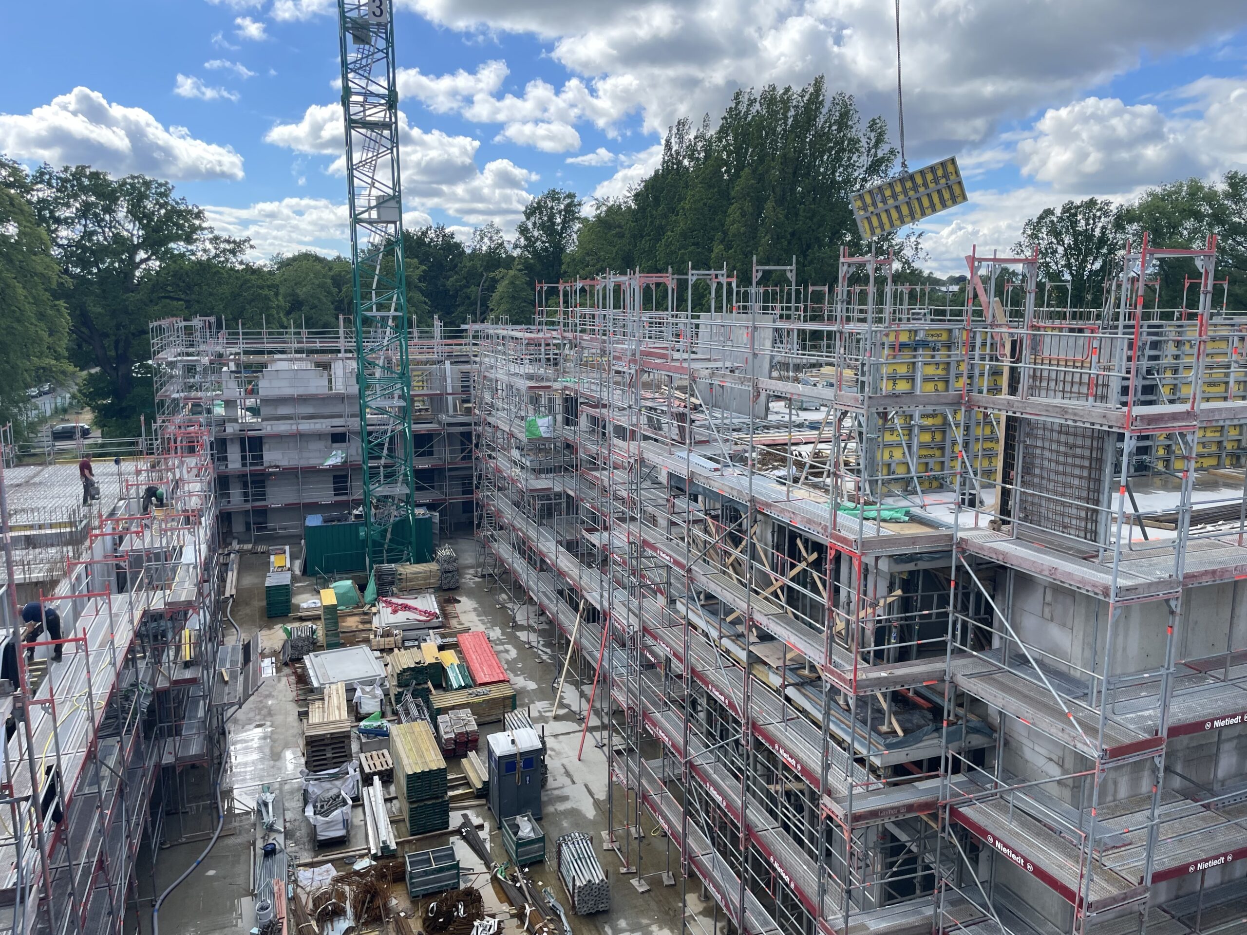 Baustelle mit Gerüsten, Kran und Baumaterialien unter bewölktem Himmel.