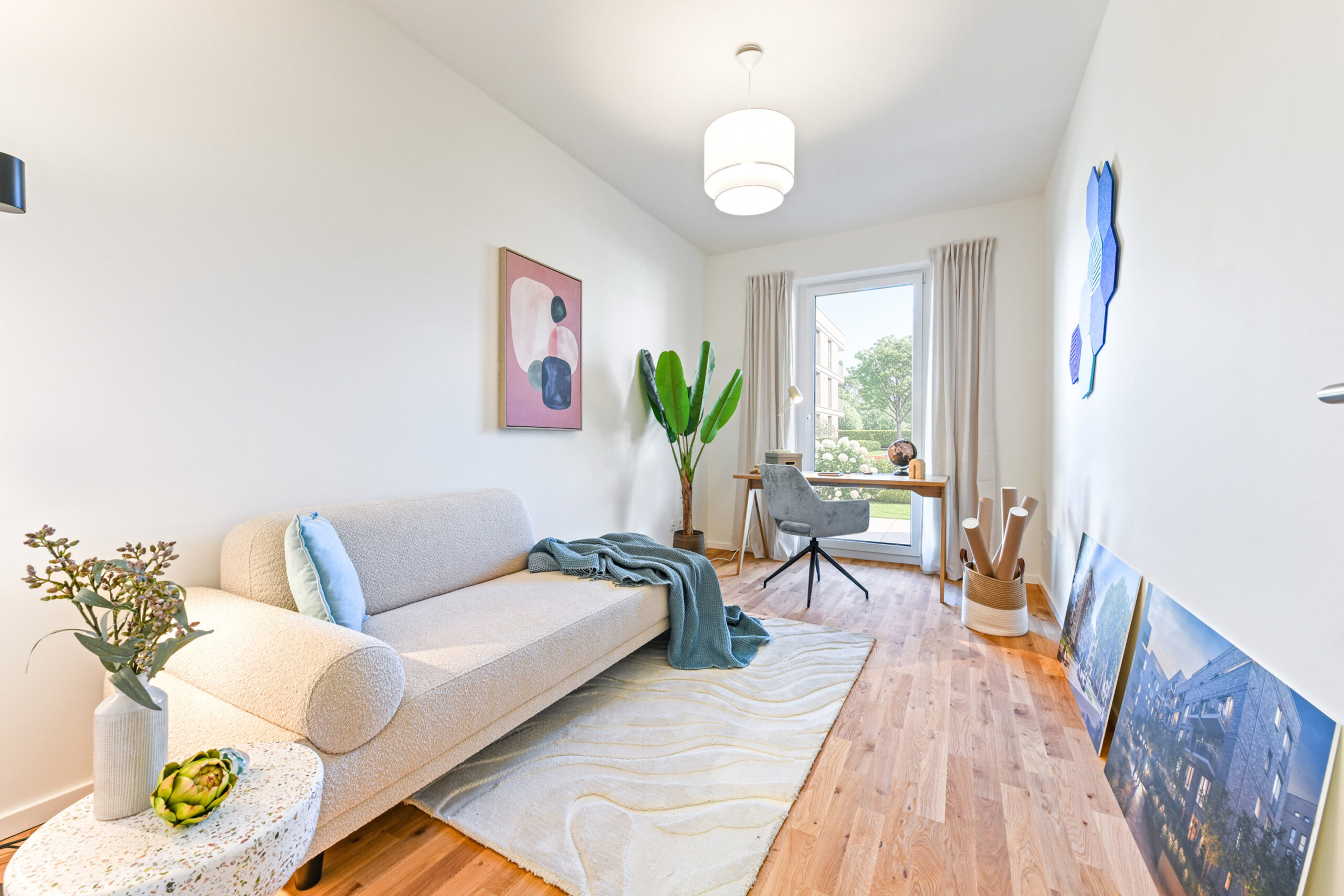 Helles, modernes Wohnzimmer mit Sofa, Schreibtisch und großem Fenster.