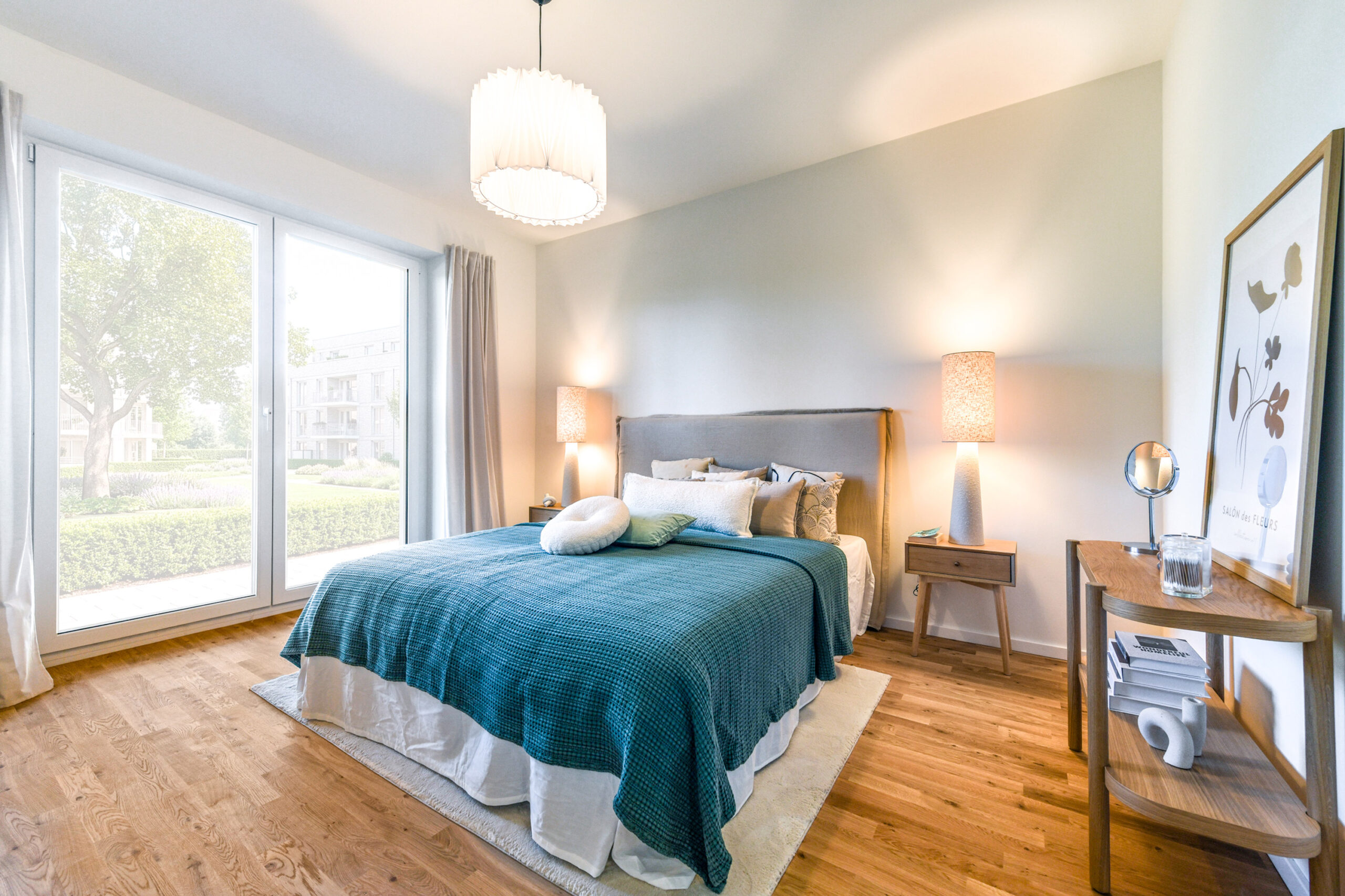 Helles Schlafzimmer mit großem Bett, Holzboden und Fensterfront zum Garten.